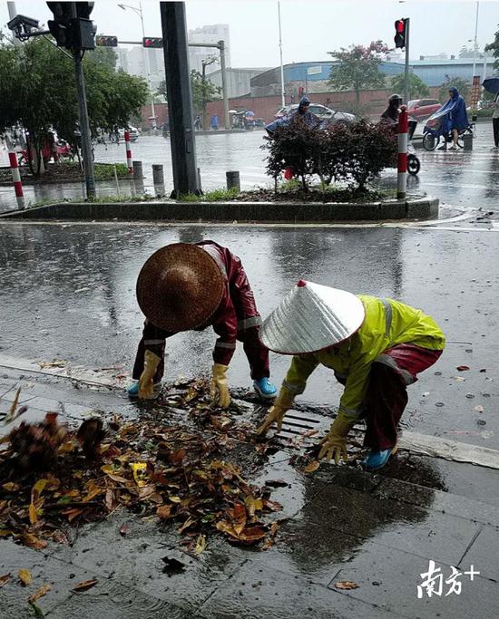 防汛人员在城市道路上排查疏通下水管道。